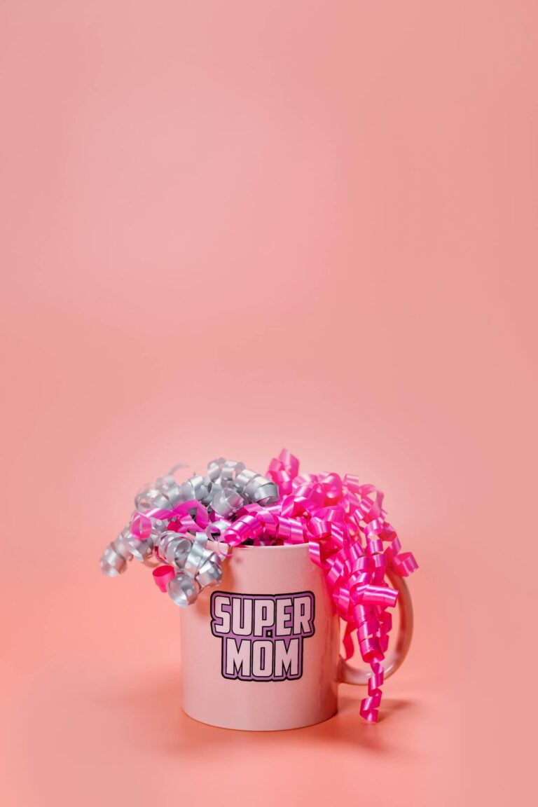 A festive Super Mom mug adorned with pink and silver ribbons on a pink background, perfect for Mother's Day gifts.