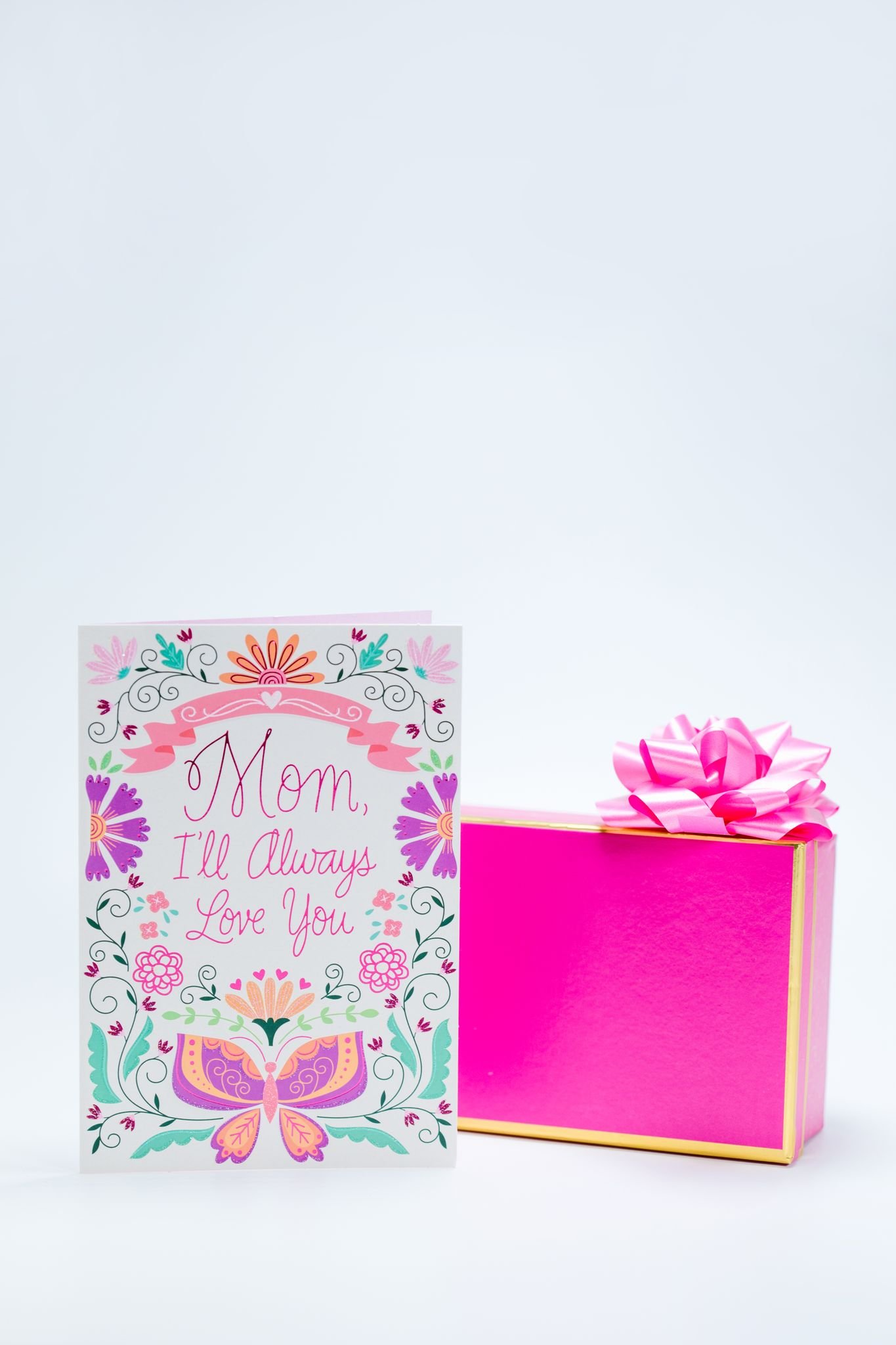 A beautifully designed Mother's Day card next to a vibrant pink gift box, perfect for showing love.